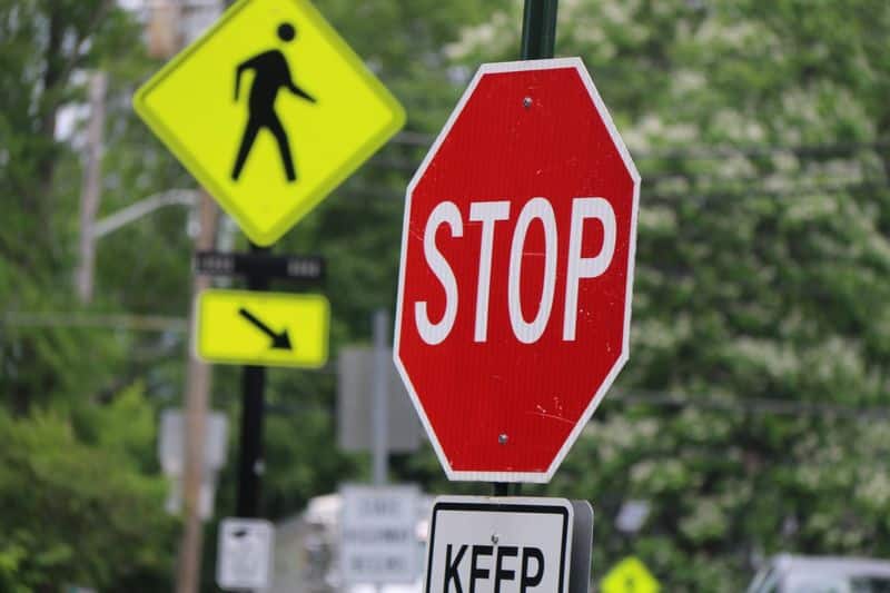 Focused view of a red stop sign with a yellow pedestrian sign in the background