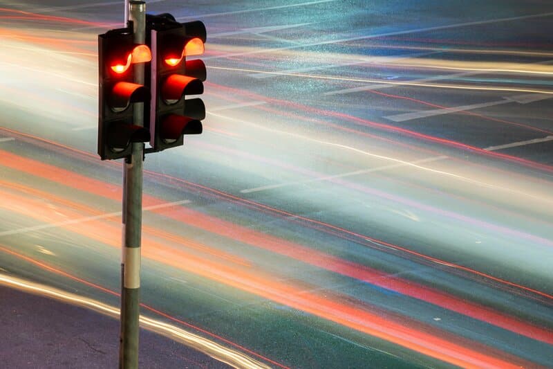 A stop light next to the blur of car headlights and tail lights