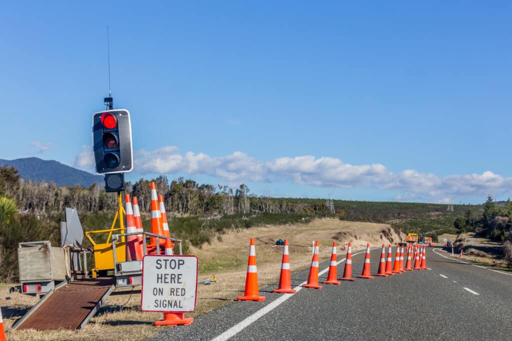 A construction site set up with orange cones, a stoplight, and other construction traffic signs to help inform drivers. https://www.123rf.com/photo_93183672_road-signs-informing-about-detour.html?vti=mlsge5t7e1sezs6242-1-5 