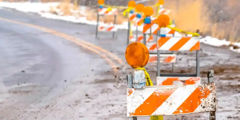 A row of Type II barricades on the side of a wet road