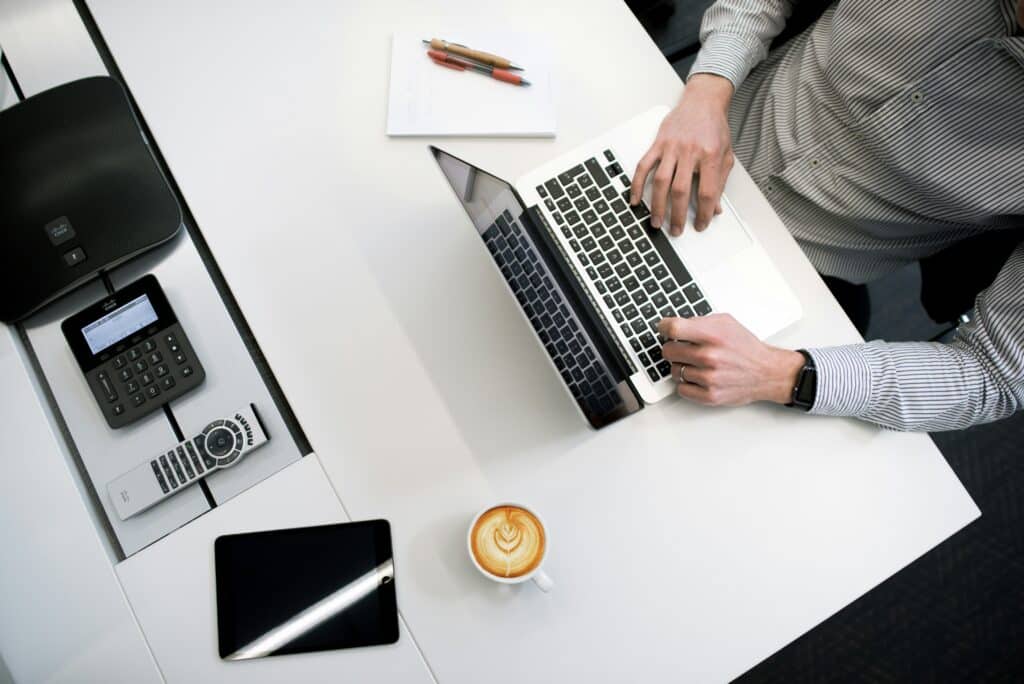 A man in a striped sleeve shirt doing his research on his laptop