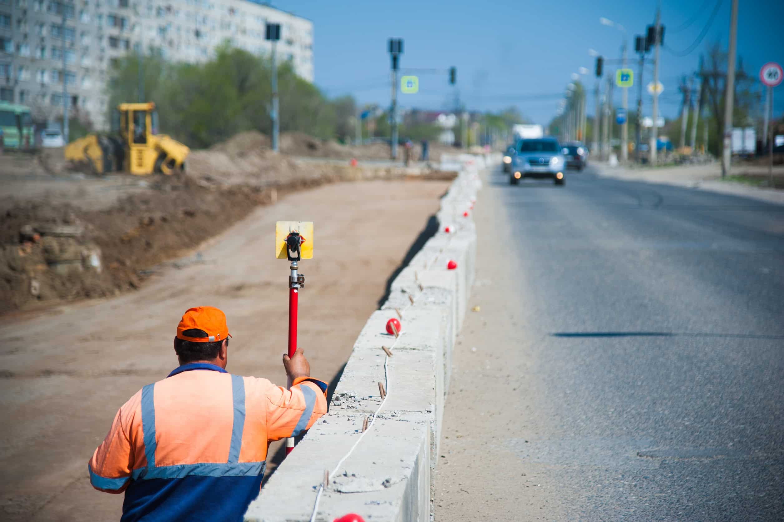 A construction worker surveying the construction of a new road using comprehensive safety solutions