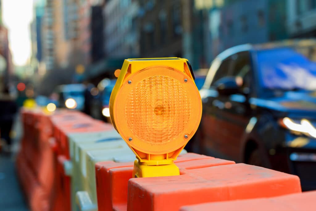 A portable traffic signal attached to an orange barricade in a construction zone