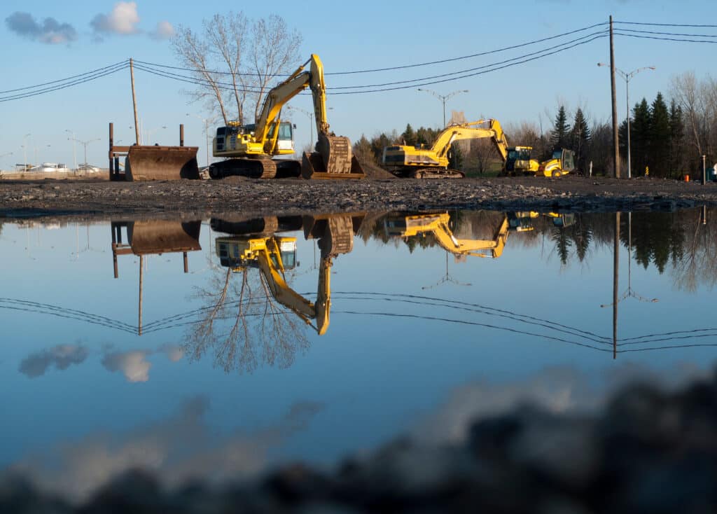 Excavator and other road construction equipment working on a construction site in the spring
