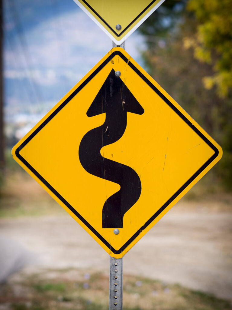 Winding road ahead sign attached to a metal breakaway sign post